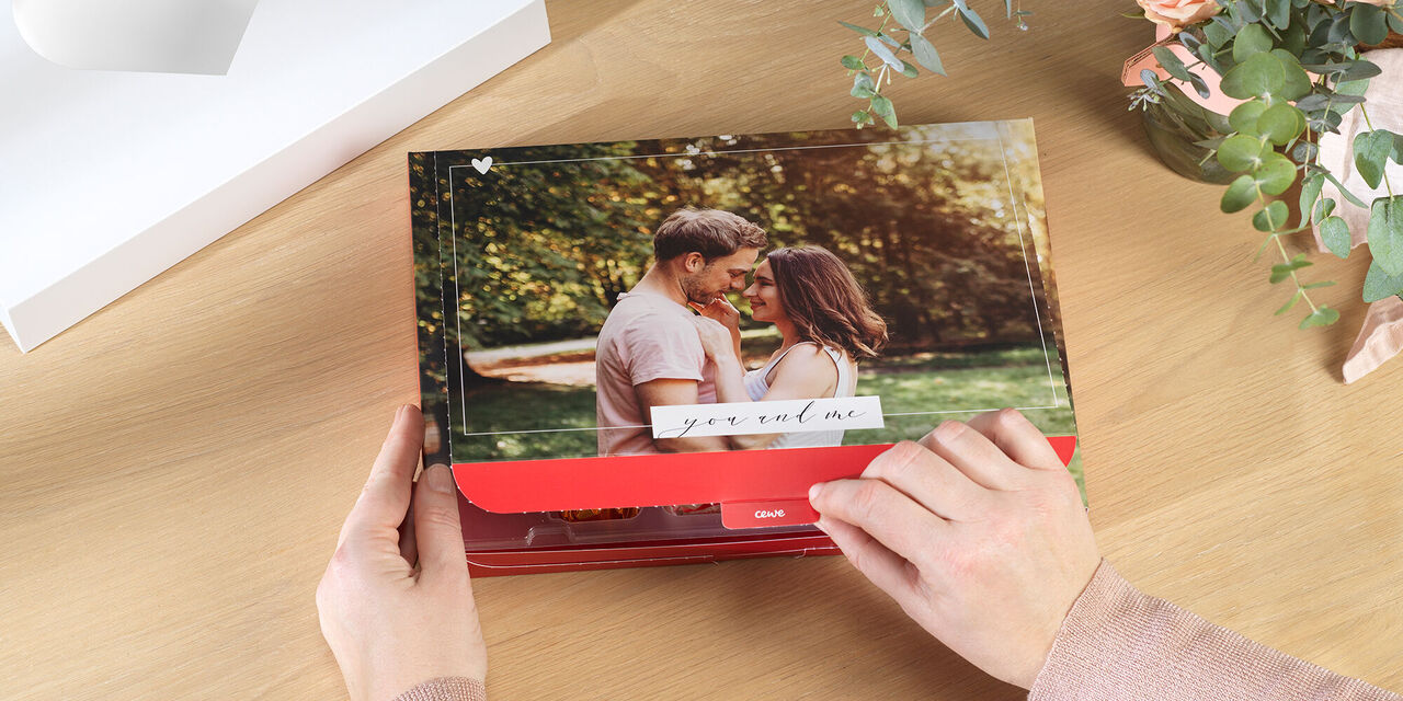 Ruce otevírají valentýnskou dárkovou krabičku s fotkou. Na víku je vidět fotka páru. Obrázek je obklopen designem, který říká „ty a já“.